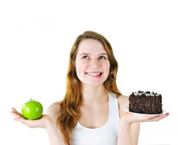 A woman choosing between an apple and cake