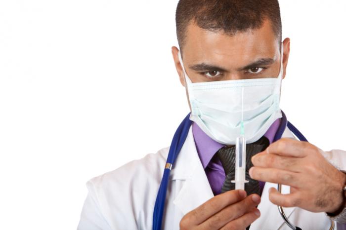 Masked doctor holding a syringe.