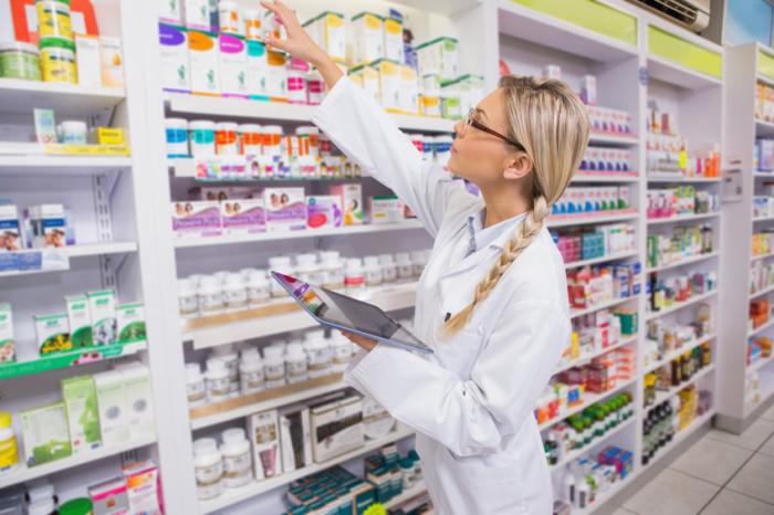 [pharmacist taking medication off the shelf]