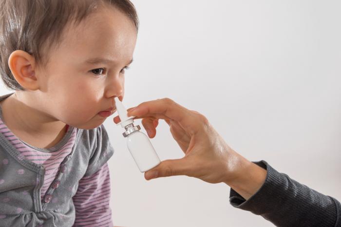 [A child being given a nasal spray vaccine]