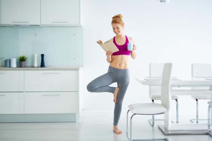 lady does exercise whilst reading and drinking a tea