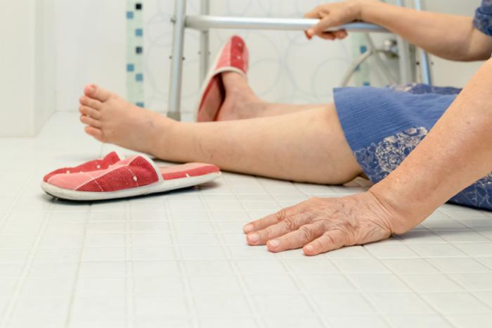 lady is sat on floor of bathroom holding zimmer frame after having a fall