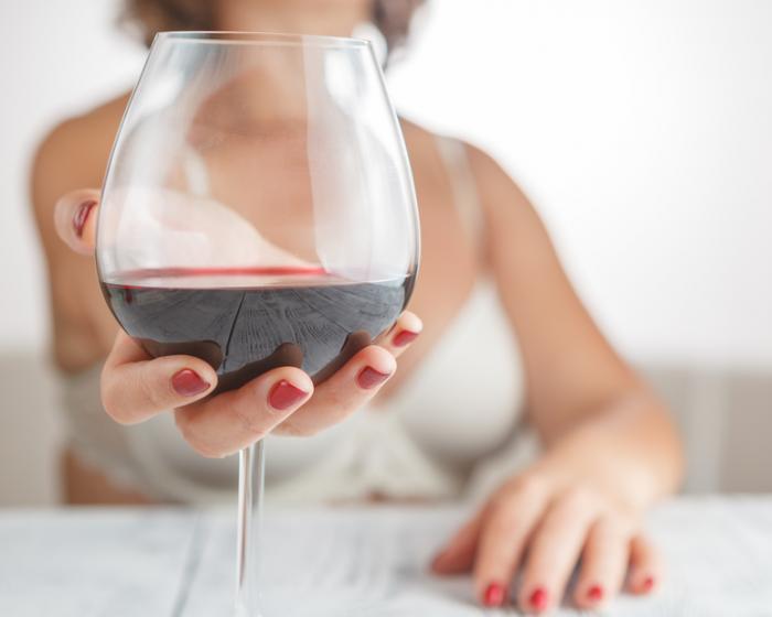 [Woman holding glass of red wine]