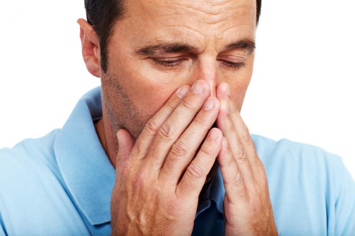 A man holds his nose with both hands