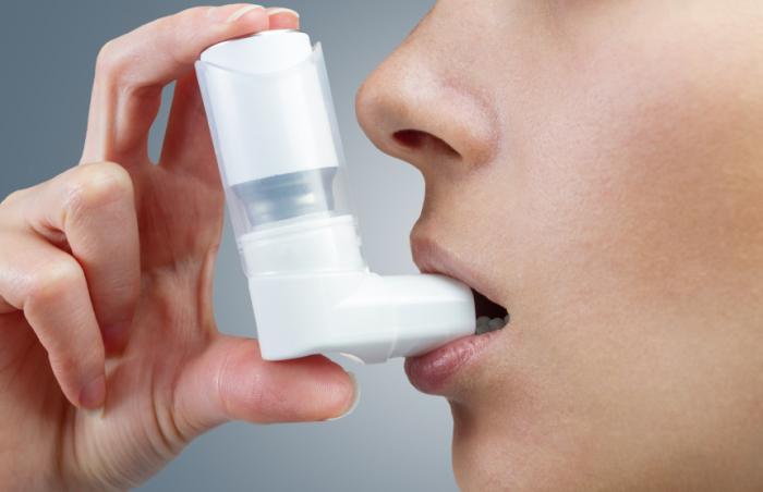 A woman uses an asthma inhaler