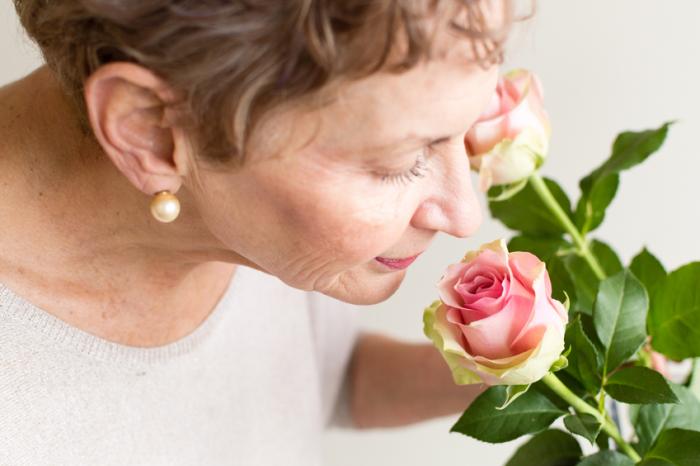 [An older woman smelling a pink rose]