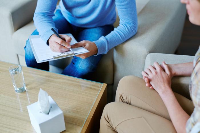 a therapist takes notes with a patient
